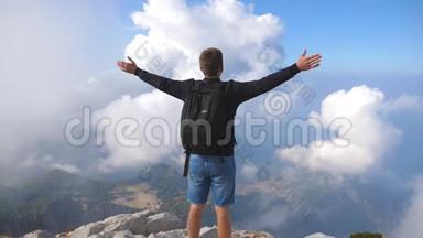 男孩游客<strong>站在山顶</strong>，胜利地伸出手臂。 在夏季旅行中享受自由的家伙